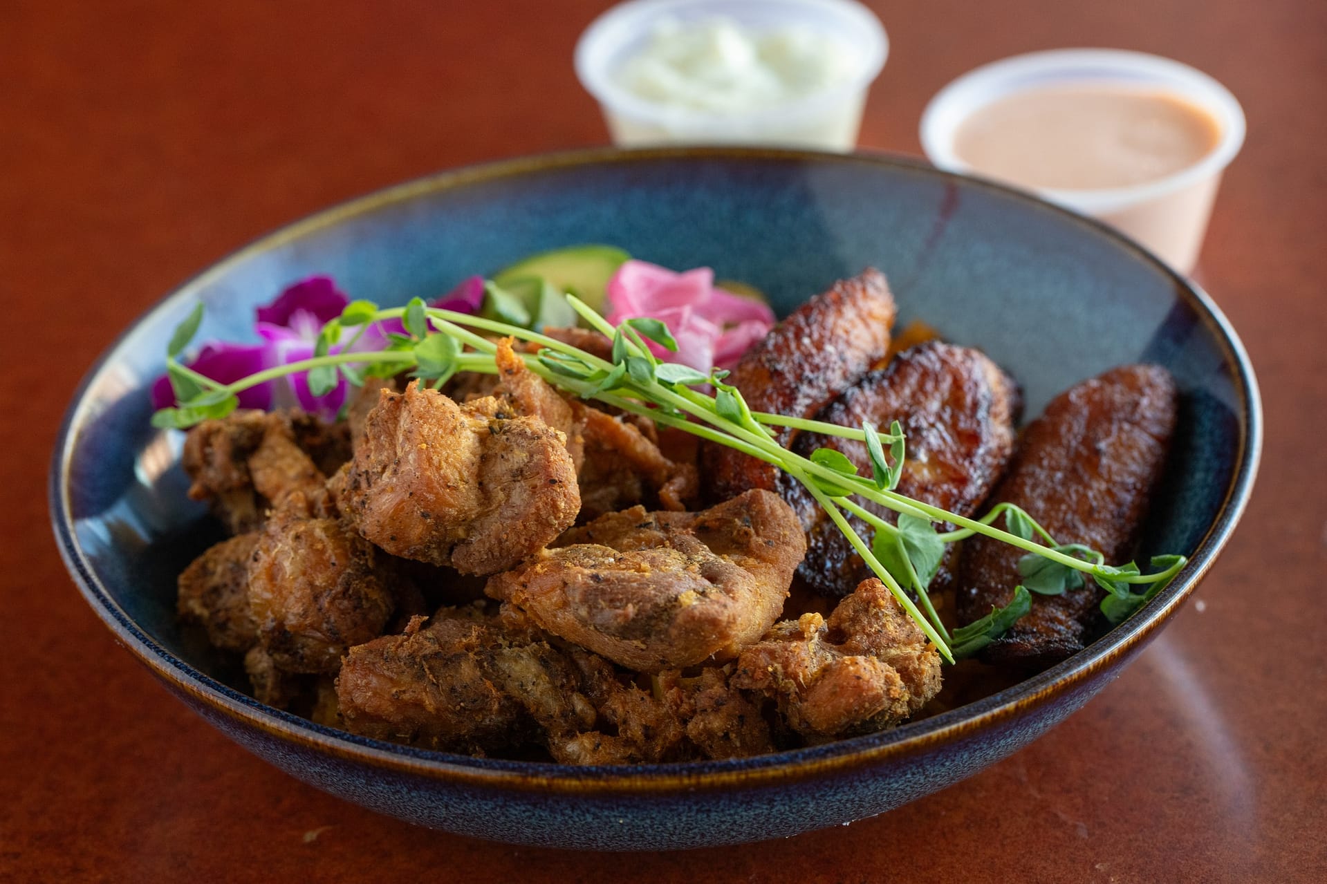 some meat and vegetables in a bowl on a table with cup of coffee